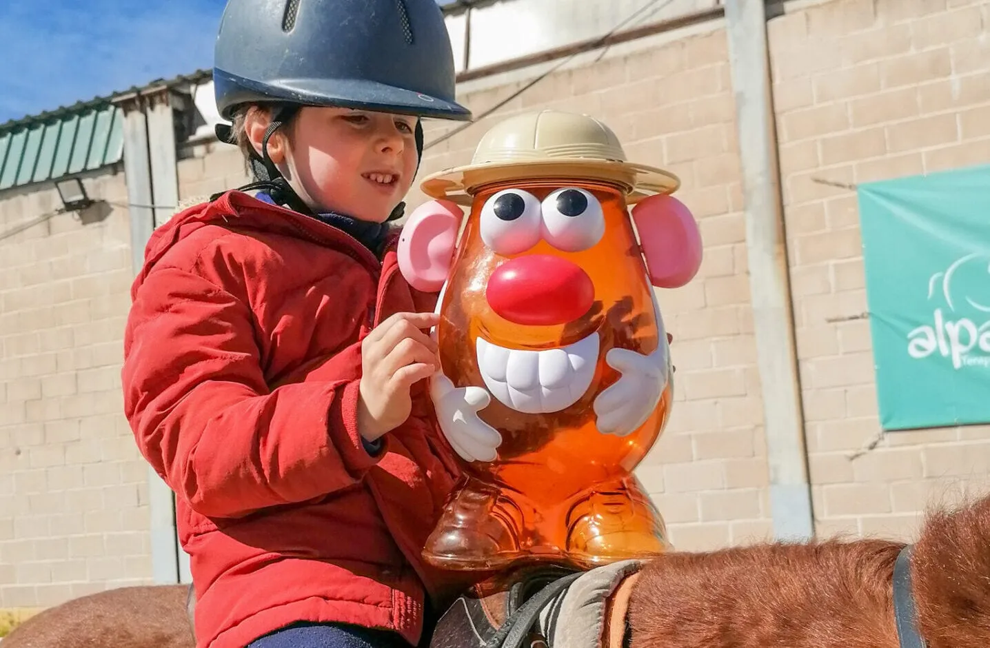 Una niña a caballo juega con material didáctico durante la sesión