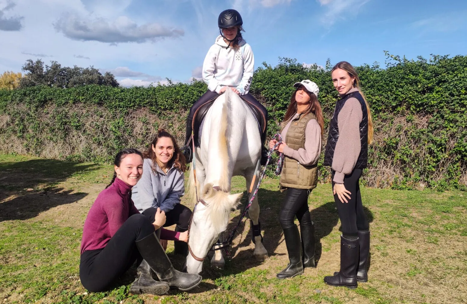 Un grupo de terapeutas y voluntarias rodea al caballo con una alumna montada