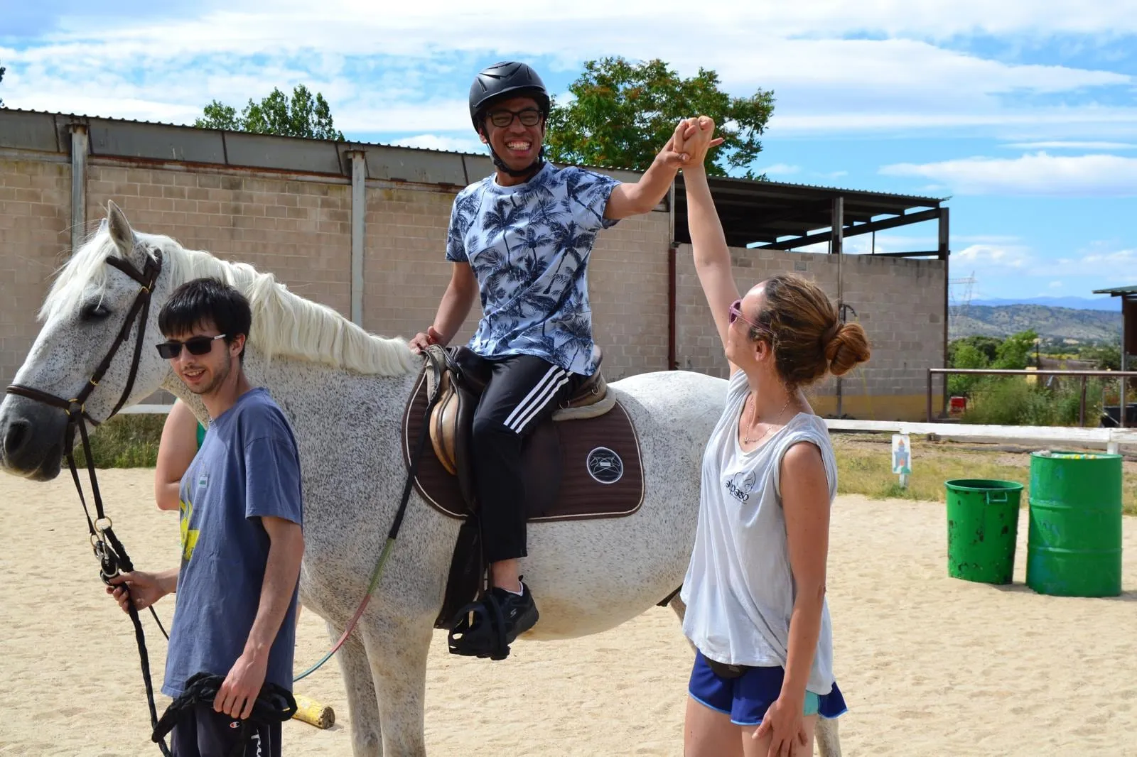 Tres jóvenes del campamento chocan la mano junto a un caballo