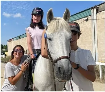 Una niña monta un caballo blanco junto a los monitores