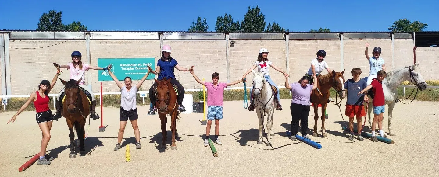 Niños y niñas del campamento de verano con los caballos en la pista