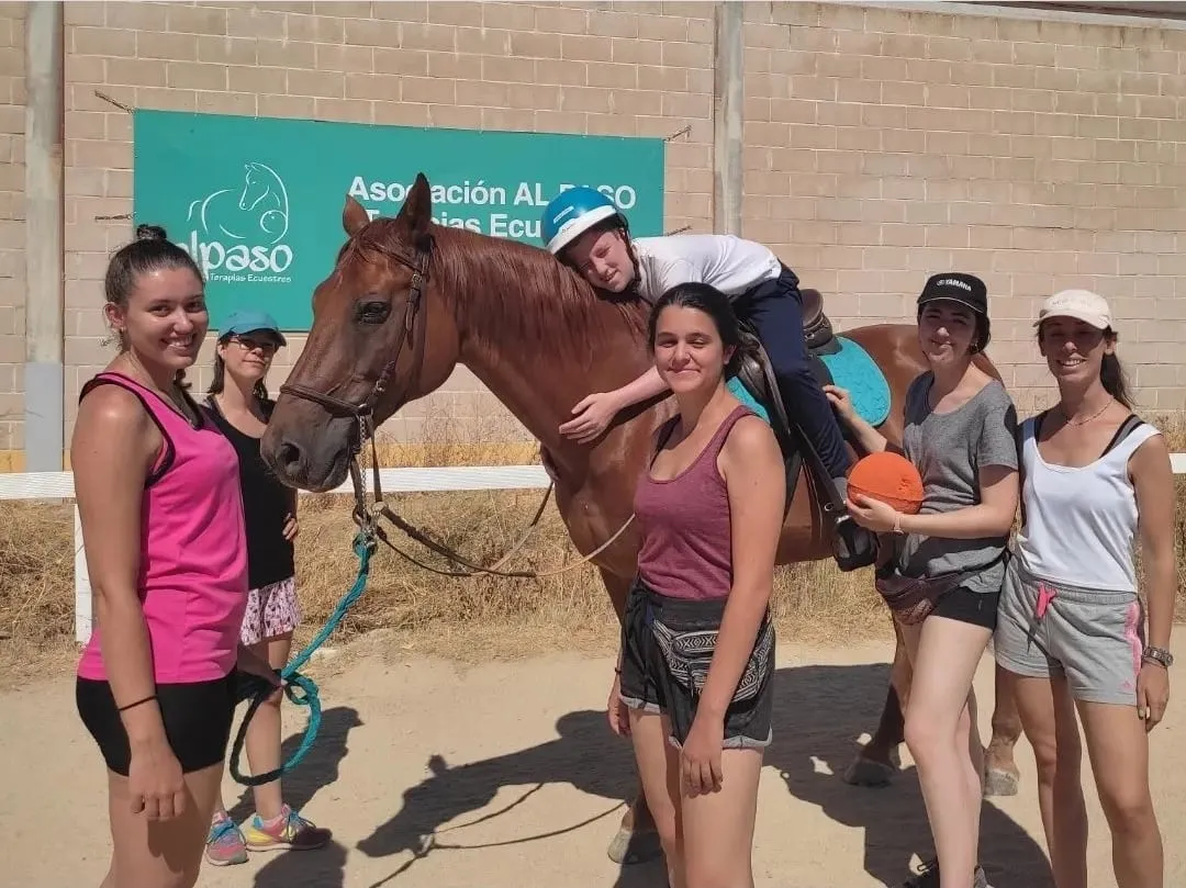 Alumnas en prácticas junto a un caballo y su jinete en la pista