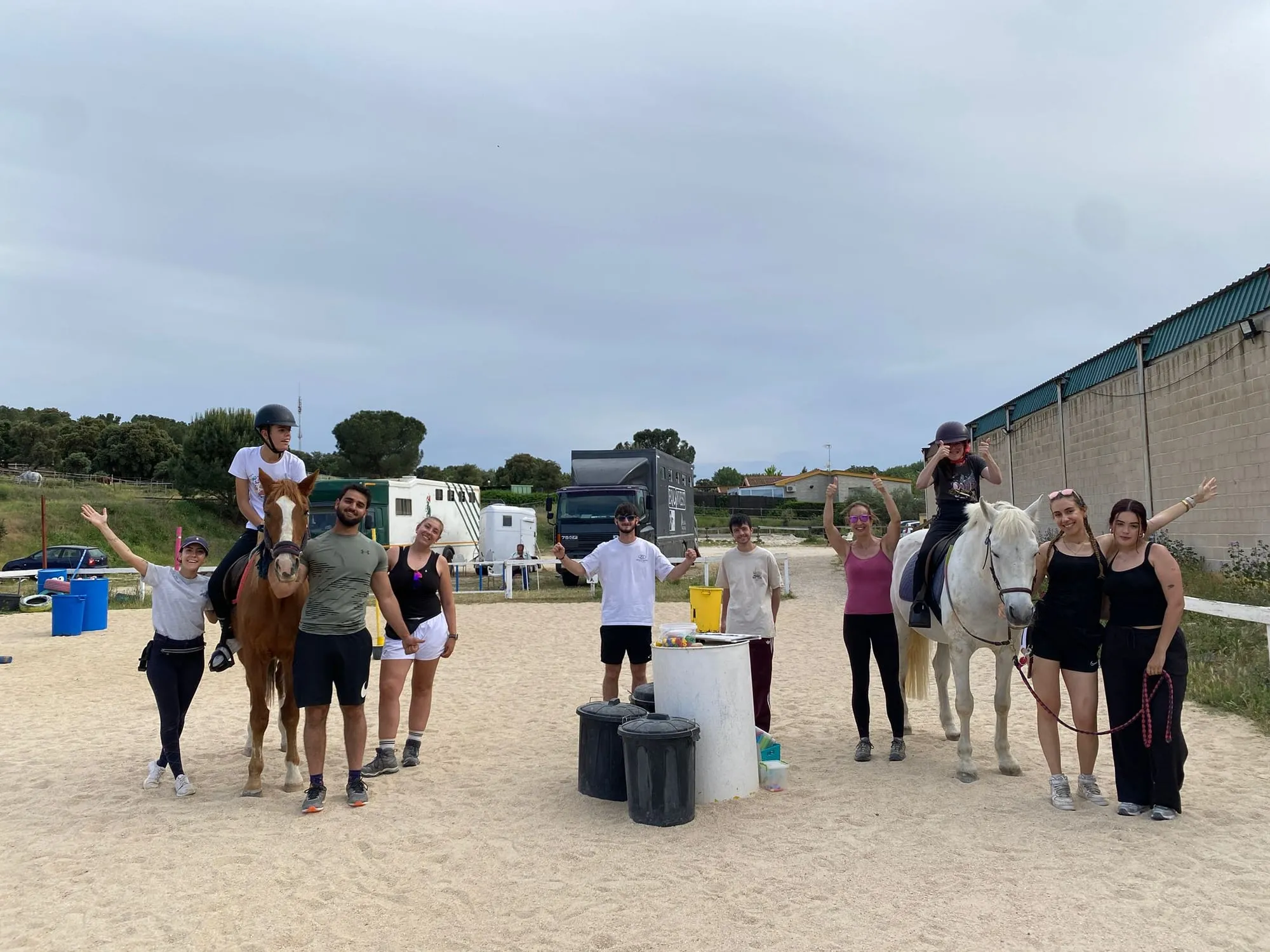 Grupo de participantes y voluntarios en la pista con dos caballos
