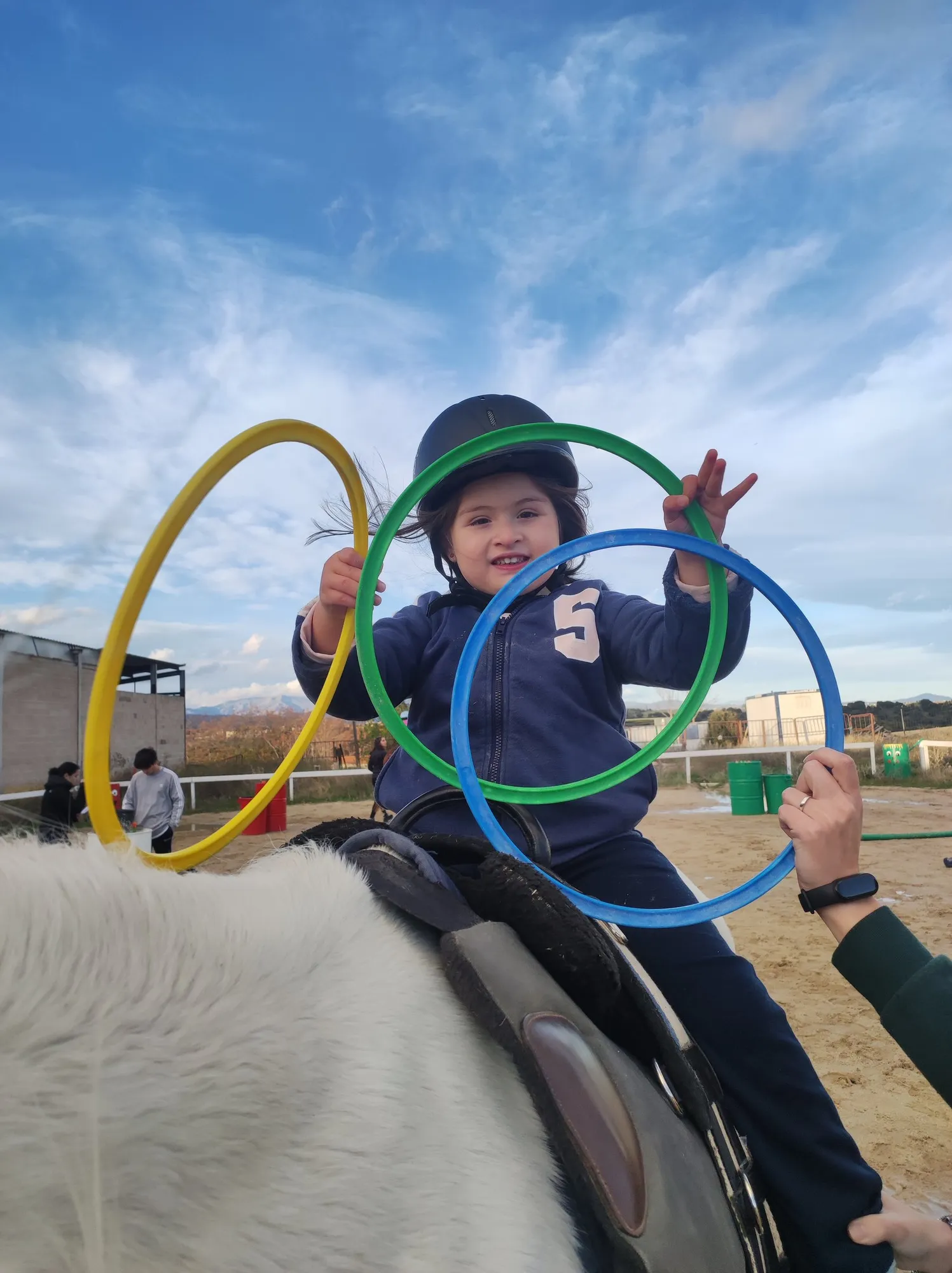 Un niño juega con aros de colores subido al caballo durante una sesión de hipoterapia