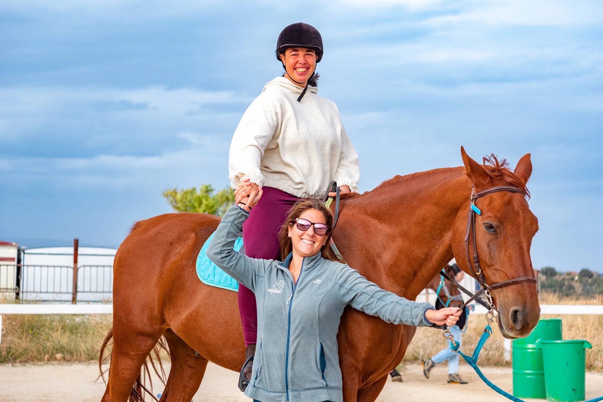 Una terapeuta y una jinete celebran junto al caballo en la pista