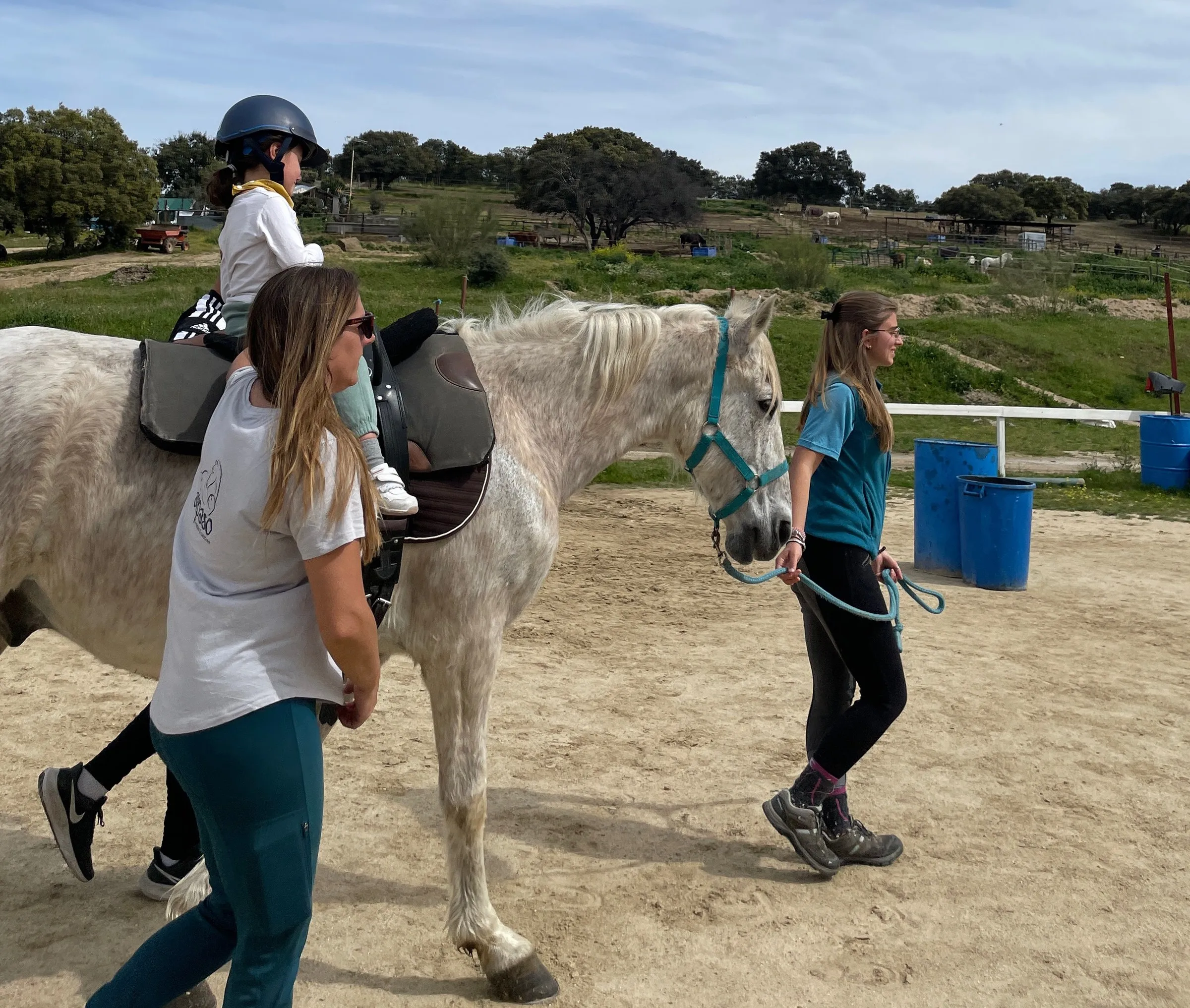 Dos terapeutas de Al Paso acompañan a un niño a caballo durante una sesión