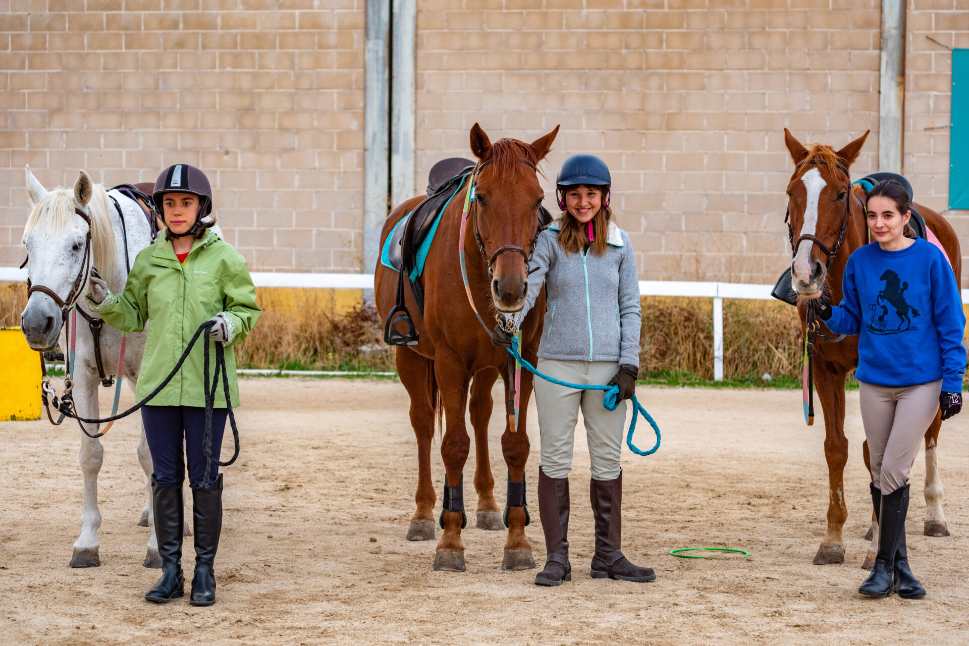 Fotografía de tres chicas con los caballos en la pista